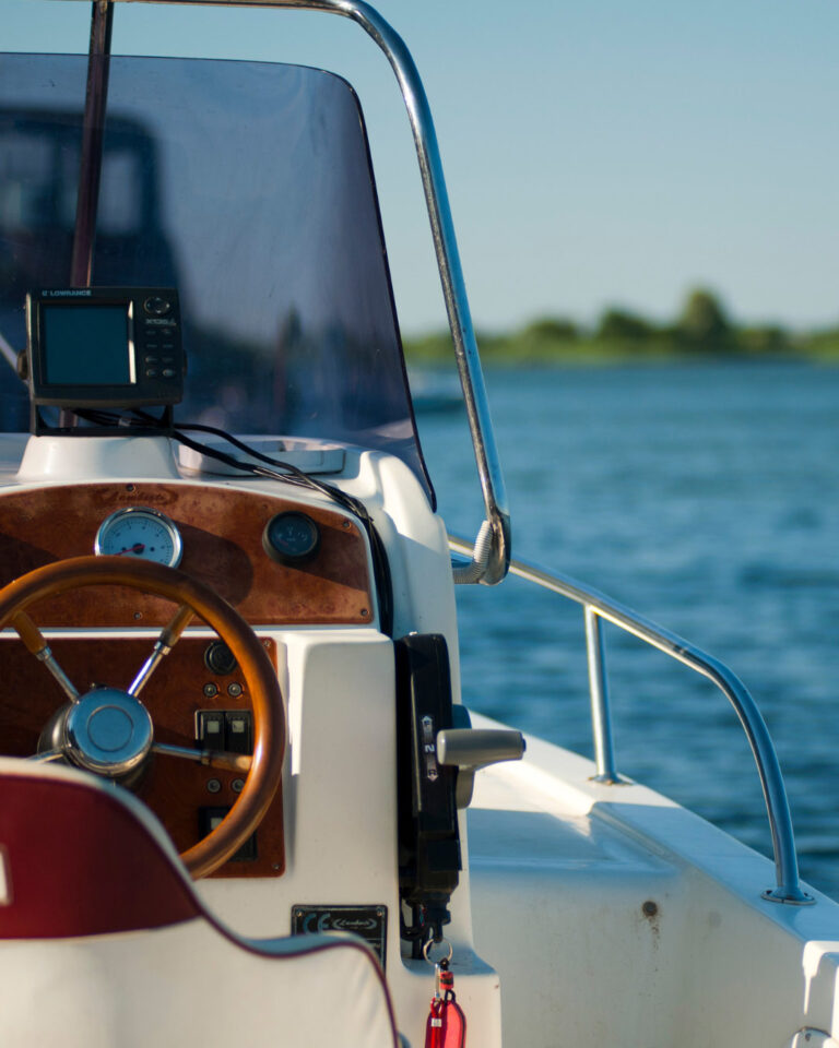 Close-up of a boat's helm with a wooden steering wheel and navigation system